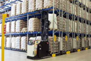 AGV gerbeur Logisnext réalisant une opération de stockage de palettes dans des rayonnages d'un entrepôt agroalimentaire.