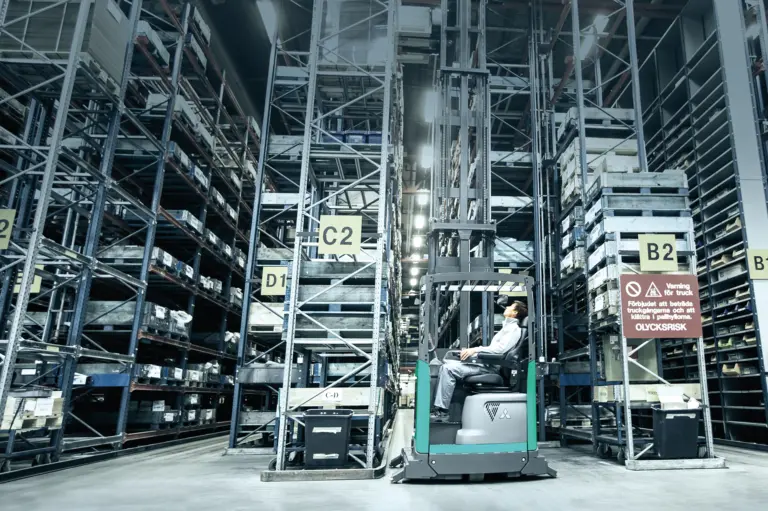 chariot à mât rétractable dans un entrepôt avec des rayonnages grande hauteur