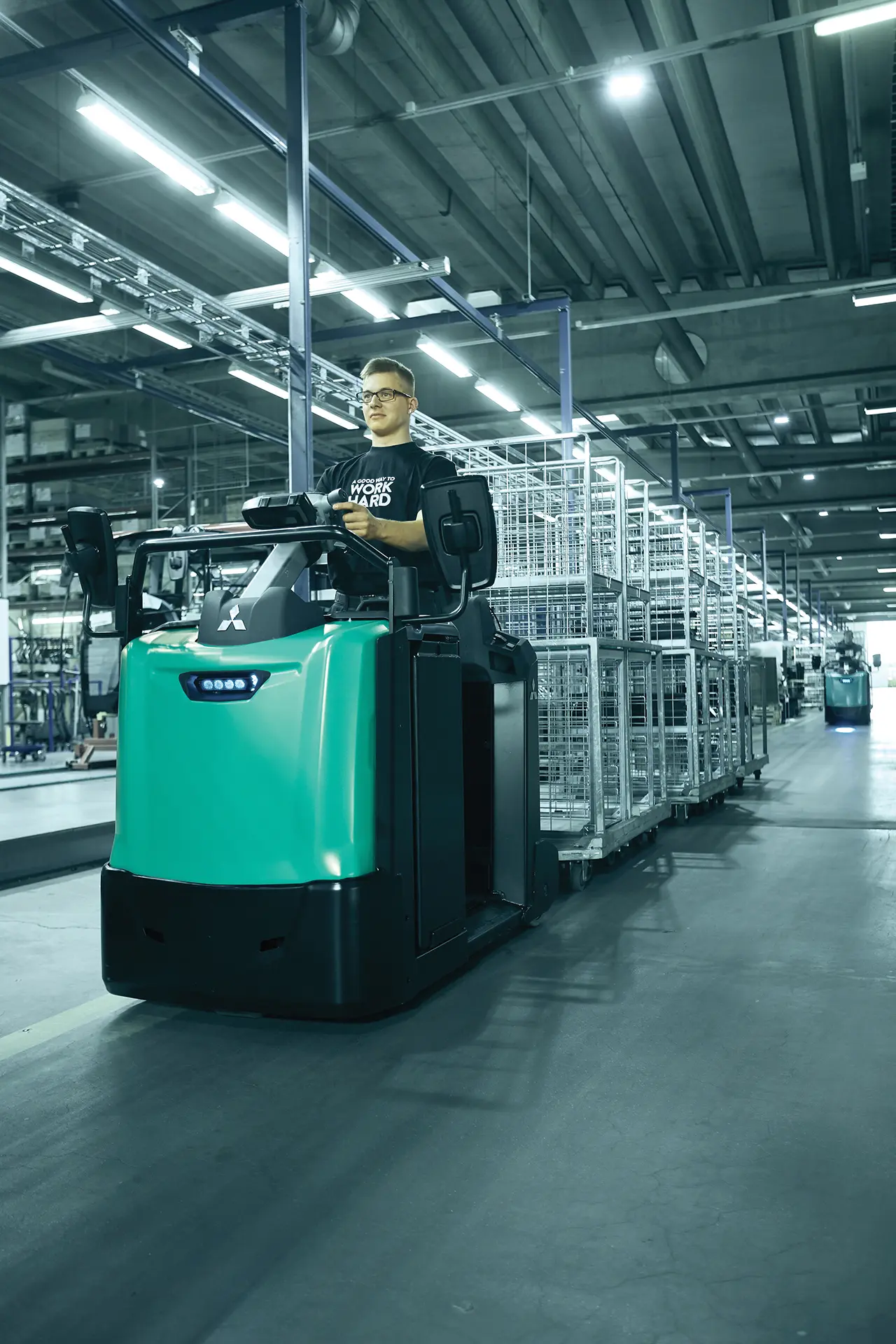 Tracteur électrique TBR30-50N2 Logisnext transportant des charges dans un entrepôt logistique.