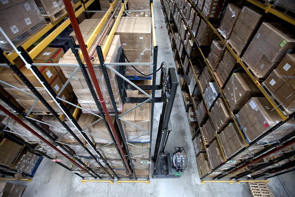 Rayonnages de stockage grande hauteur avec chariot rétractable dans un entrepôt logistique.