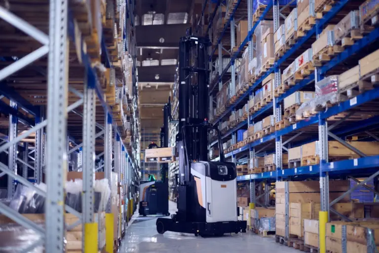 AGV Logisnext circulant entre des rayonnages de stockage dans un entrepôt logistique.
