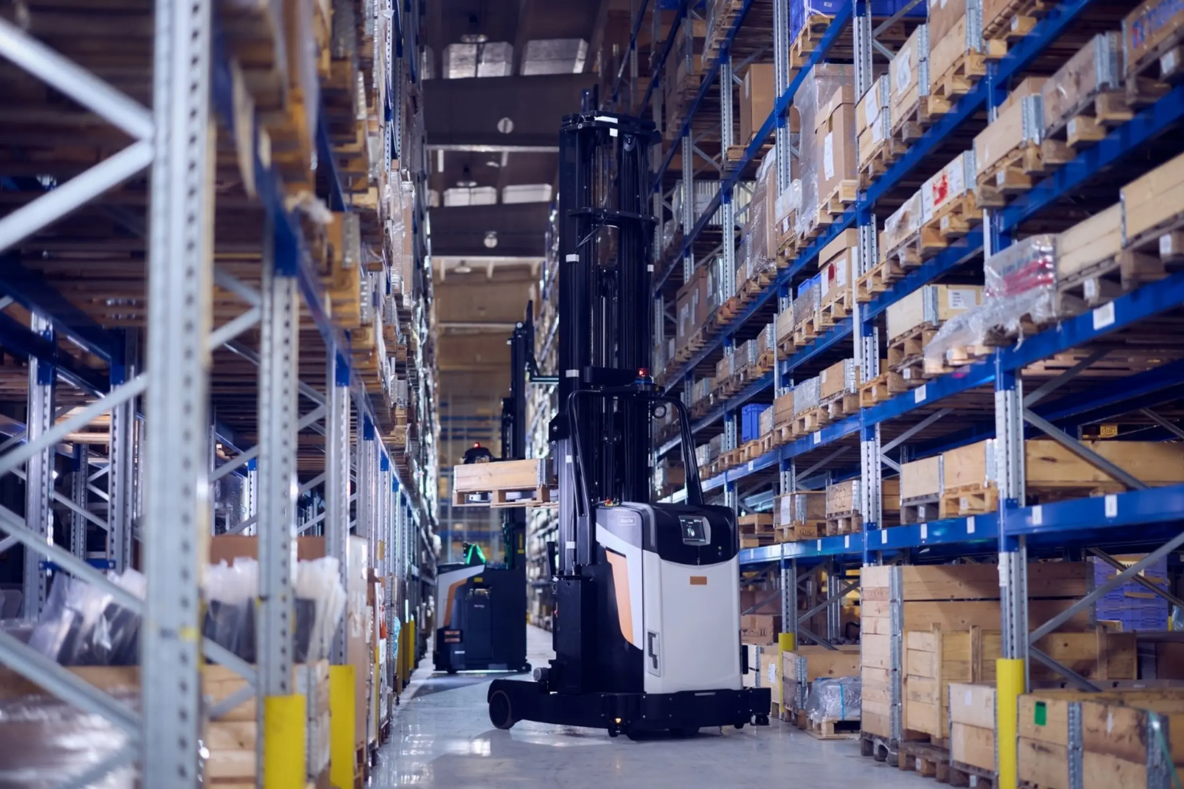 AGV Logisnext circulant entre des rayonnages de stockage dans un entrepôt logistique.