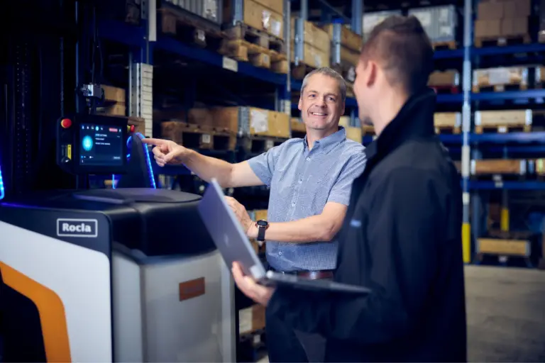 Techniciens Logisnext entretenant un équipement automatisé dans un entrepôt logistique.