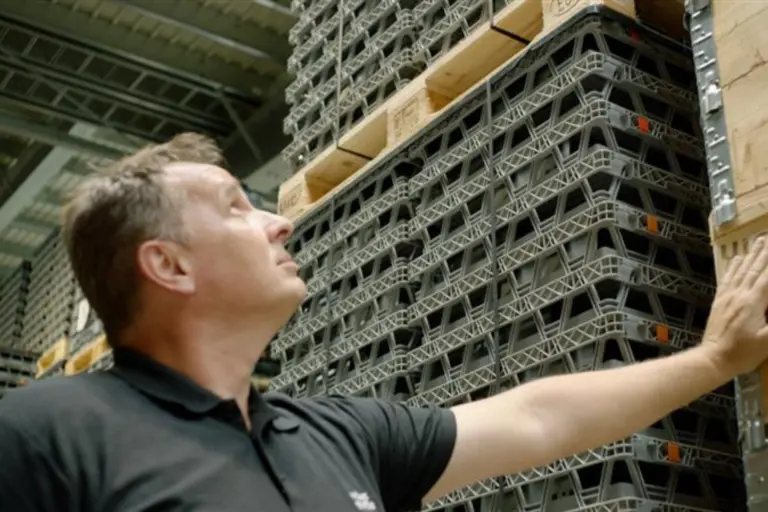 Opérateur vérifiant des marchandises stockées sur des rayonnages dans un entrepôt logistique.