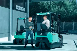 Chariot élévateur électrique Logisnext présenté devant un bâtiment professionnel avec plusieurs personnes à proximité.