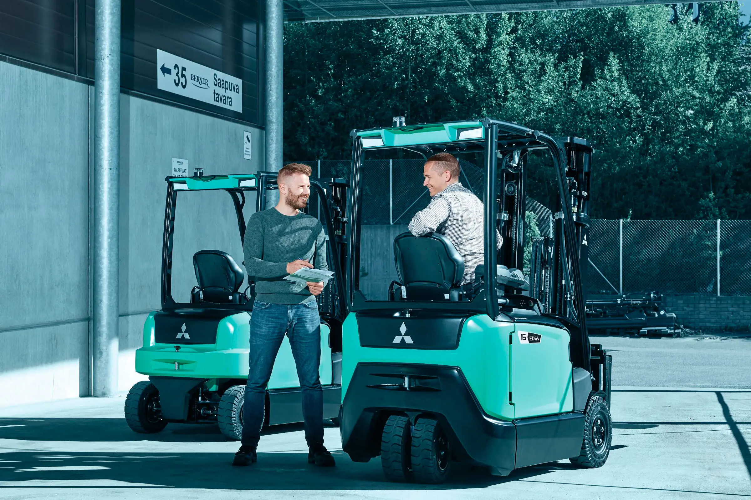 Chariot élévateur électrique Logisnext présenté devant un bâtiment professionnel avec plusieurs personnes à proximité.