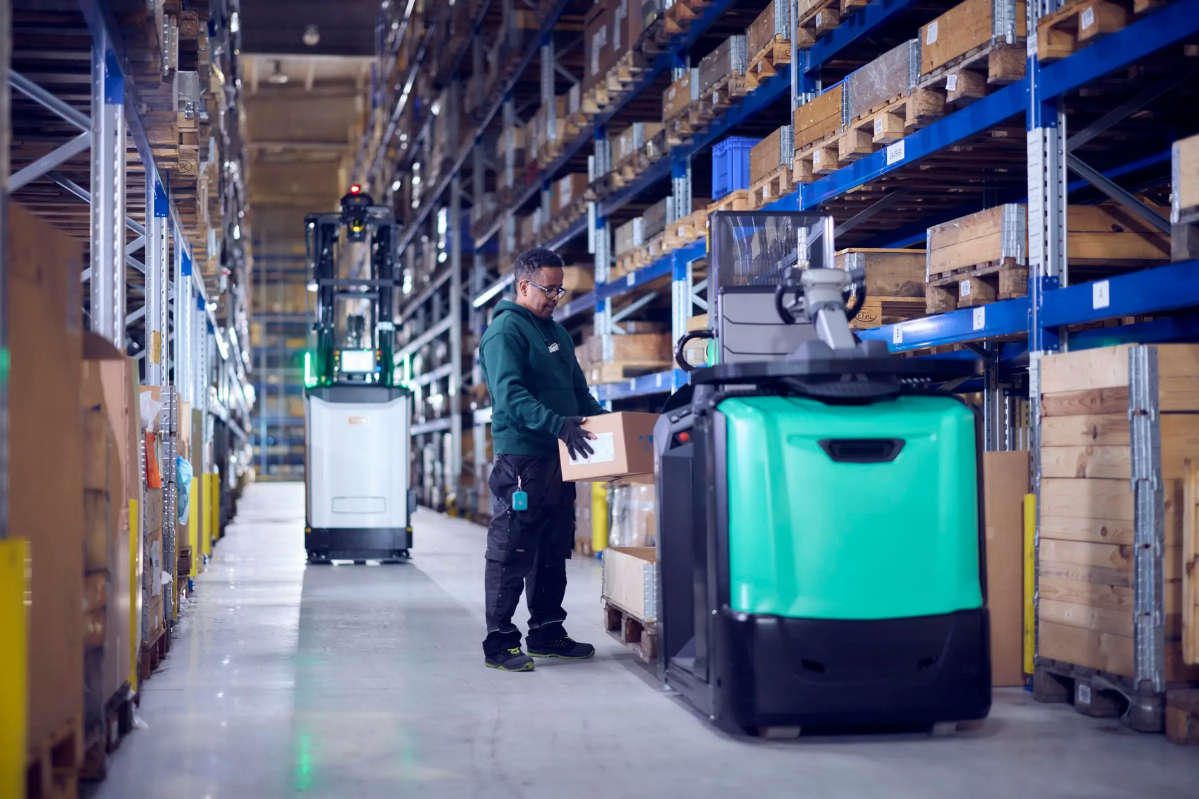 préparateur de commandes dans une allée d'un entrepôt avec un chariot automatisé