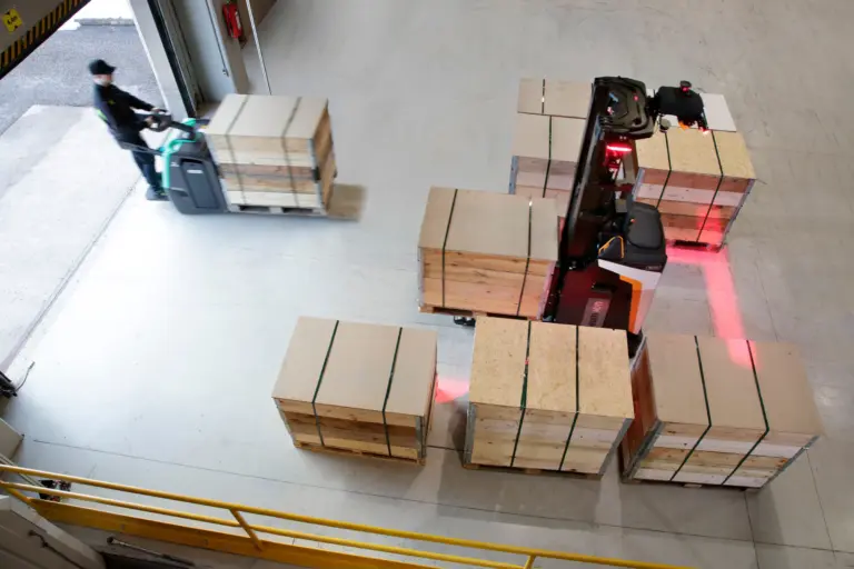 Vue aérienne d'un chariot automatisé transportant des palettes et des colis sur une zone de manutention.