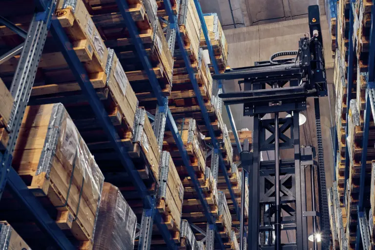 AGV à mât rétractable Logisnext réalisant une opération de stockage dans des rayonnages grande hauteur.