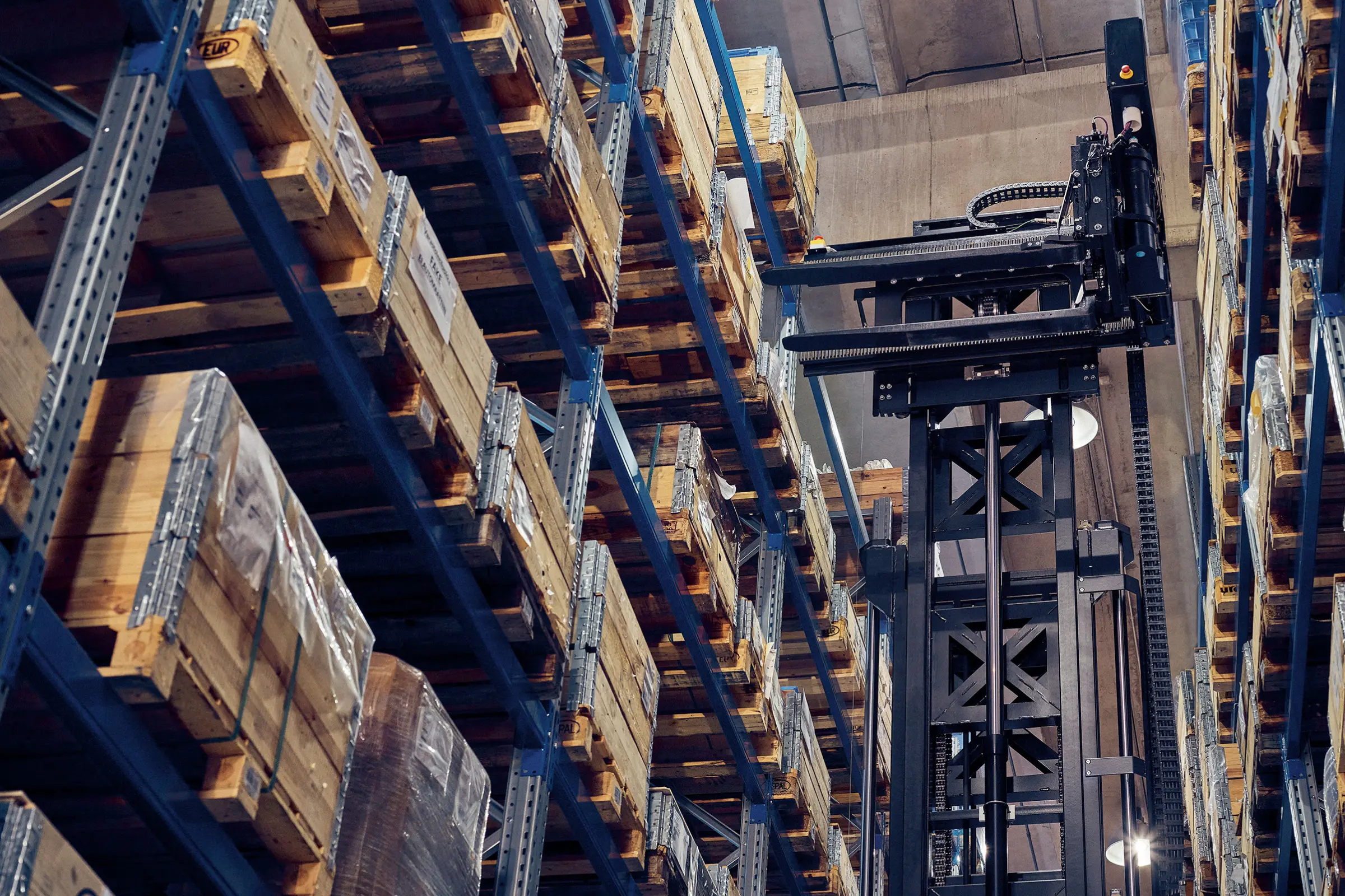 AGV à mât rétractable Logisnext réalisant une opération de stockage dans des rayonnages grande hauteur.