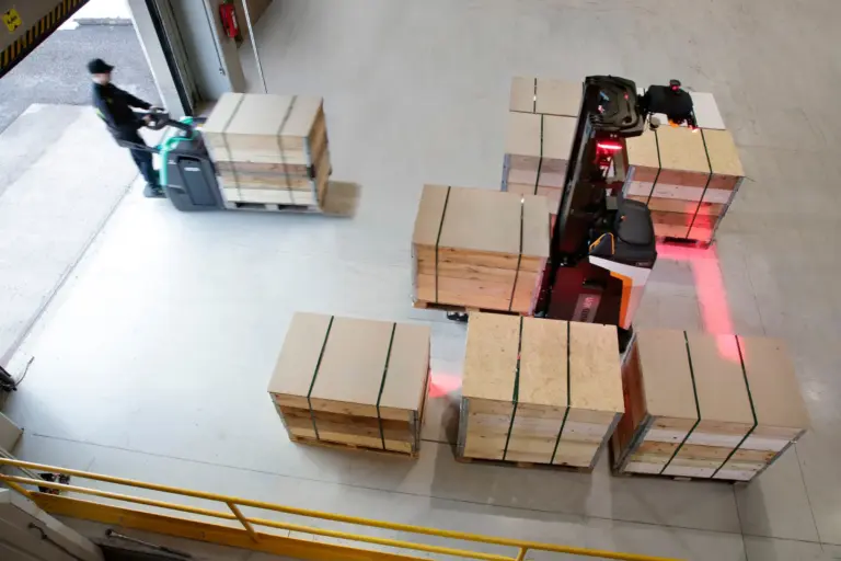 Chariot automatisé transportant des palettes et des colis dans une zone logistique.